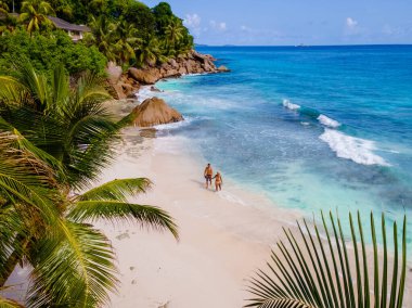 Anse Patates, La Digue Seychelles, Seyşeller 'de lüks bir tatil sırasında tropik bir plajda yaşayan genç bir çift. Tropik sahil Anse Patates, La Digue Seyşeller