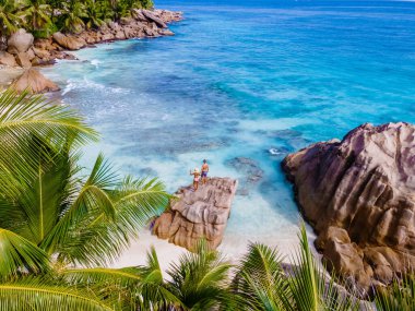 Anse Patates, La Digue Seychelles, Seyşeller 'de lüks bir tatil sırasında tropik bir plajda yaşayan genç bir çift. Tropik sahil Anse Patates, La Digue Seyşeller