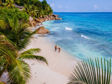 Anse Patates, La Digue Seychelles, Seyşeller 'de lüks bir tatil sırasında tropik bir plajda yaşayan genç bir çift. Tropik sahil Anse Patates, La Digue Seyşeller insansız hava aracı görüntüsü