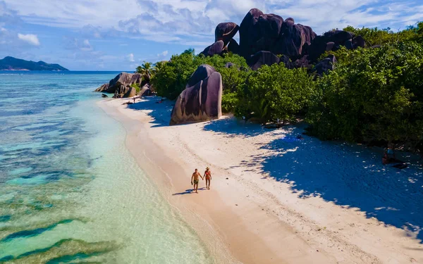 Anse Source dArgent, La Digue Seychelles, Seyşeller 'de lüks bir tatil sırasında tropikal bir plajda birkaç kadın ve erkek. Tropik sahil Anse Kaynak dArgent, La Digue Seyşeller