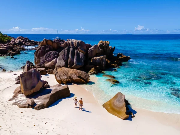 セイシェルで豪華な休暇中にトロピカルビーチで男性と女性の若いカップルであるAnse Coco Digue Seychelles 青い海とトロピカルビーチアンセコスラディグセイシェル — ストック写真