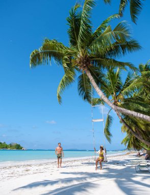 Bir çift kadın ve erkek tropikal bir sahilde palmiye ağacının altında salıncakla Anse Volbert Praslin adasında Seyşeller 'in havadan görünüşü Anse Volbert Cote dOr plajında. 