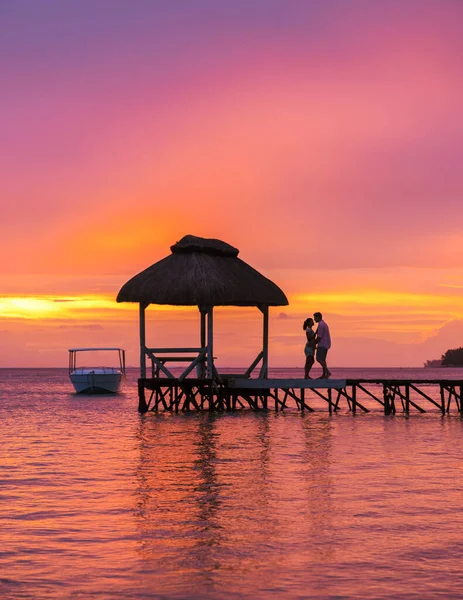 一对男女在毛里求斯热带海滩上的一个木制码头观看日落 一对夫妇在毛里求斯度蜜月 — 图库照片