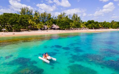 Mauritius tatili, Mauritius 'ta mavi bir okyanusta kanoyla gezen çift. Balayı tatili sırasında Mauritius Adası 'nın turkuaz renkli okyanusunda seyyar satıcılık yapan erkekler ve kadınlar.