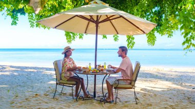 Mauritius 'ta tropik bir plajda kahvaltı yapan erkek ve kadın. Mauritius' ta balayı tatili yapan bir çift.