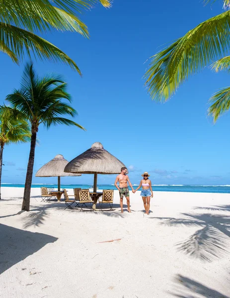在毛里求斯的热带海滩上 男人和女人有海滩椅子和棕榈树 一对夫妇在毛里求斯的黎莫尔纳海滩度蜜月 背景是黎莫尔纳山 — 图库照片