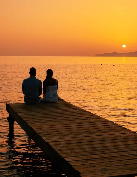 Ett Par Män Och Kvinnor Träbrygga Tittar Färgglada Solnedgången Havet — Stockfoto