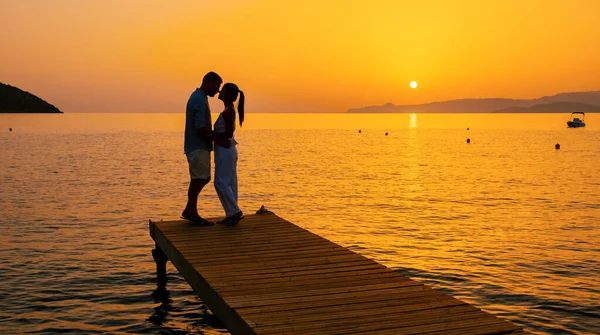 Ett Par Män Och Kvinnor Träbrygga Tittar Färgglada Solnedgången Havet — Stockfoto