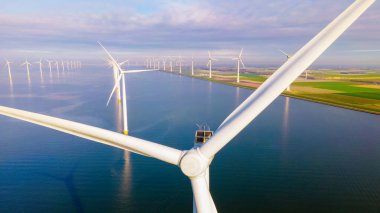 Bulutları ve mavi gökyüzü olan off-shore yel değirmeni parkı, rüzgar türbini Flevoland Hollanda 'nın deniz manzaralı yel değirmeni parkı Ijsselmeer. Hollanda 'da güneşli bir günde Yeşil Enerji