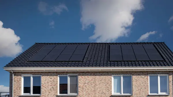 新建房屋 屋顶上有太阳能电池板 与阳光灿烂的天空相对照 用黑色太阳能电池板将新建筑围起来 Zonnepanelen Zonne Energie Translation Solar Panel — 图库照片