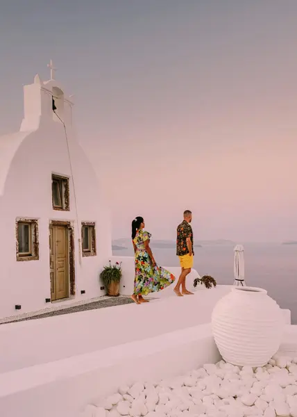 圣托里尼希腊 一对年轻夫妇在圣托里尼岛上观看蓝色穹顶教堂的日出 并在暑假期间观看粉刷过的希腊奥亚圣托里尼村的日出 — 图库照片