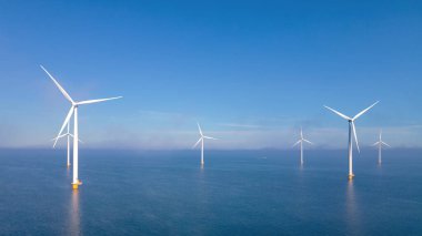 Bulutlu ve mavi gökyüzü olan yel değirmeni parkı, okyanus havası manzaralı rüzgar türbini yeşil enerji üretimi Hollanda 'da