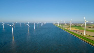 Bulutlu ve mavi gökyüzü olan yel değirmeni parkı, okyanus havası manzaralı rüzgar türbini yeşil enerji üretimi Hollanda 'da