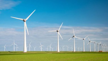 Bulutları ve mavi gökyüzü olan rüzgar değirmeni parkı, okyanusta yel değirmeni türbinleri