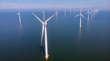 Okyanus açıklarındaki yel değirmeni çiftliği Westermeerwind Parkı 'ndaki yel değirmenleri Hollanda Flevoland Noordoostpolder' ın güneşli bir gününde denizde izole edilmiş.