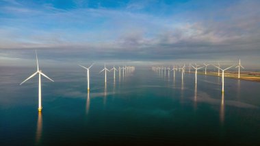 Bulutları ve mavi gökyüzü olan yel değirmeni parkı, okyanusta rüzgar türbinleri Nehterland 'deki bir rüzgar çiftliğinin havadan görünüşü temiz enerji üretiyor.