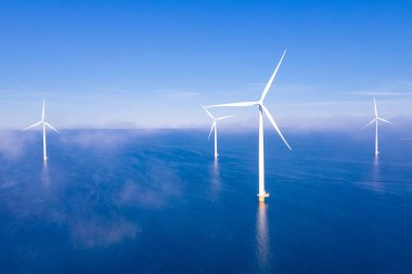 Fırtınalı bulutları, mavi gökyüzü, okyanusta yel değirmeni parkı olan açık deniz yel değirmeni parkı. Hollanda Avrupa