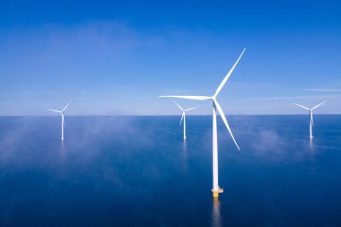 Okyanus açıklarındaki yel değirmeni çiftliği Westermeerwind Parkı 'ndaki yel değirmenleri Hollanda Flevoland Noordoostpolder' ın güneşli bir gününde denizde izole edilmiş.