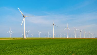 Bulutlu ve mavi gökyüzü olan yel değirmeni parkı, okyanus havası manzaralı rüzgar türbini yeşil enerji üretimi Hollanda 'da