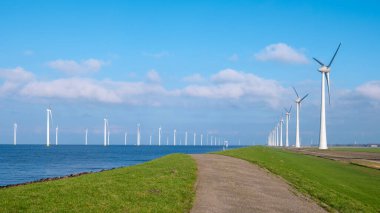 Açık deniz yel değirmeni parkı bulutlu ve mavi gökyüzü, okyanus havası manzaralı rüzgar türbini Flevoland Hollanda Ijsselmeer. 