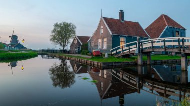 Hollanda 'nın tarihi ahşap çiftlikleri olan Hollanda köyünde bahar boyunca yel değirmeni köyünde gün batımı.