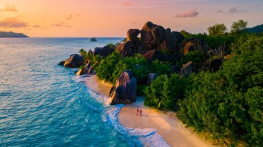 Anse Source dArgent, La Digue Seychelles, Seyşeller 'de lüks bir tatil sırasında tropikal bir plajda yaşayan genç bir çift. Tropik sahil Anse Kaynak dArgent, La Digue Seyşeller