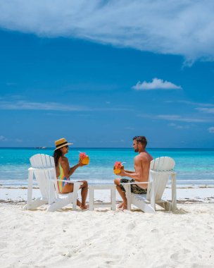 Hindistan cevizli iki erkek ve kadın sahilde Praslin Seyşeller içiyorlar. Beyaz plajları ve palmiye ağaçları olan tropik bir ada. Anse Volbert Seyşeller plajı..