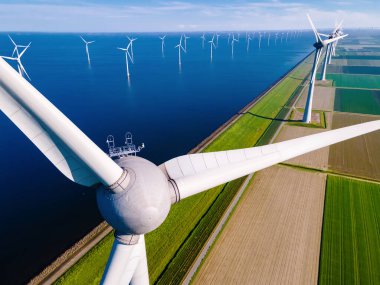 Mavi gökyüzü, yeşil tarım arazisi ve okyanusta yel değirmeni türbinleri parkı olan yel değirmeni parkı. Hollanda Avrupa 'nın Hollanda' daki en büyük rüzgar parkı