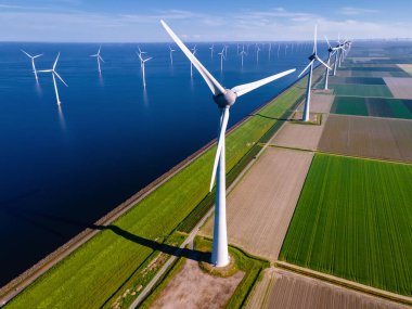 Mavi gökyüzü olan yel değirmeni parkı, okyanusta yel değirmeni türbinleri. Hollanda