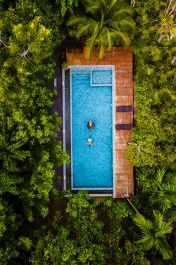 Krabi Tayland 'ın ormanındaki bir yüzme havuzunun insansız hava aracı görüntüsü, Tayland ormanındaki bir yüzme havuzunun üzerinde insansız hava aracı. Havuzda yukarıdan bir çift kadın ve erkek.