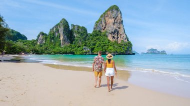 Railay Beach Krabi Tayland, Railay Krabi 'nin tropikal plajı, kumsalda bir çift kadın ve erkek, güneşli bir günde Tayland' da huzurlu bir Railay Sahili manzarası.
