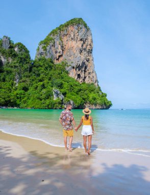 Railay Beach Krabi Tayland, Railay Krabi 'nin tropikal plajı, kumsalda bir çift kadın ve erkek, güneşli bir günde Tayland' da huzurlu bir Railay Plajı manzarası. 