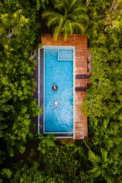 aerial drone view of a swimming pool in the jungle of Krabi Thailand, aerial view with a drone above a swimming pool in the jungle of Thailand. couple of men and women in the pool from above
