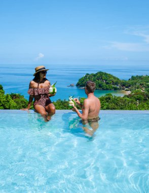  Bir çift adam ve bir kadın Tayland 'da havuz kenarında lüks bir tatil yapıyorlar. Bir çift de Tayland' da tropik bir adada balayına çıkıp okyanusu seyrediyorlar.