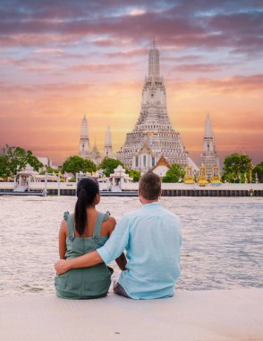 Tayland 'da gün batımında Bangkok' taki Wat Arun Tapınağı. Gün batımında Chao Praya Nehri. Bir çift adam ve bir kadın Bangkok Tayland 'a şehir gezisine gittiler. Nehir kenarında gün batımını izliyorlar.