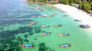 Koh Lipe Adası Güney Tayland. Turkuaz renkli okyanusları ve beyaz kumlu plajları var. Okyanusta uzun kuyruklu tekneleri var.