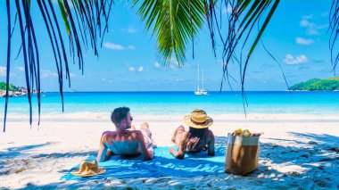 Praslin Seyşeller tropikal adasında plajlar ve palmiye ağaçları var. Seyşeller 'de tatilde olan iki erkek ve kadın. Anse Lazio Praslin Seyşeller' in tropik plajını ziyaret ediyorlar..