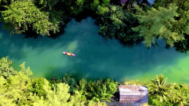 两名男子和女子在热带岛屿泰国高昌的皮划艇上 在日落时分在热带森林中的一条热带河流上俯瞰皮划艇 — 图库视频影像