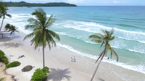 在泰国高库特岛 一对夫妇在高库德岛的海滩上散步 这里是一个热带海滩 阳光明媚 有棕榈树和草屋色的海洋 — 图库视频影像