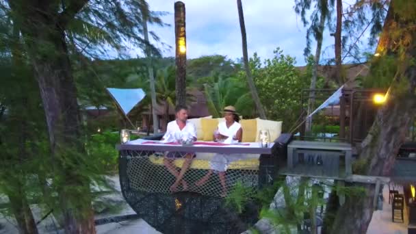 いくつかの男性と女性は コッド島タイトラットの高級ホテルでビーチで夕食をとっています 鳥の巣の日没でビーチで多様なカップルディナー — ストック動画