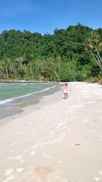 在一个阳光明媚的日子里 在泰国高库德岛的海滩上散步的亚洲妇女 在一个阳光明媚的日子里 泰国高库德岛是一个拥有棕榈树和草屋色海洋的热带海滩 — 图库视频影像