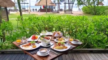 Plajda okyanus manzaralı lüks kahvaltı masası. Tayland 'da lüks bir otel. Ekmek, yumurta, kahve ve meyve suyu olan bir kahvaltı masası.