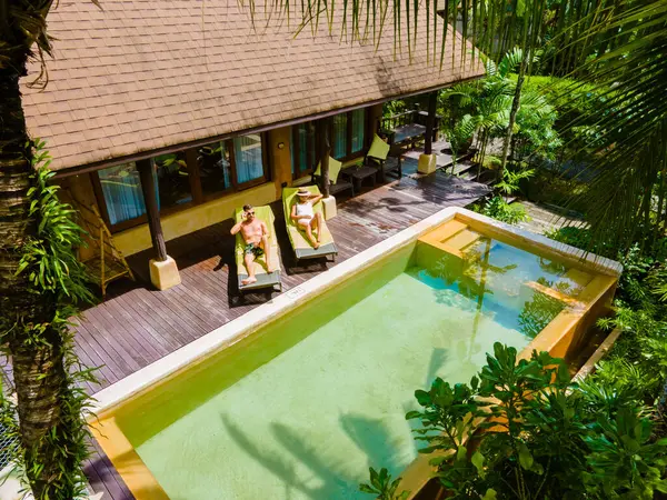 スイミングプール付きの家 モダンなプールヴィラ タイの豪華ヴィラ タイの豪華な休暇で男性と女性のカップル 休日の間にプールでリラックスする5つ星リゾートで — ストック写真