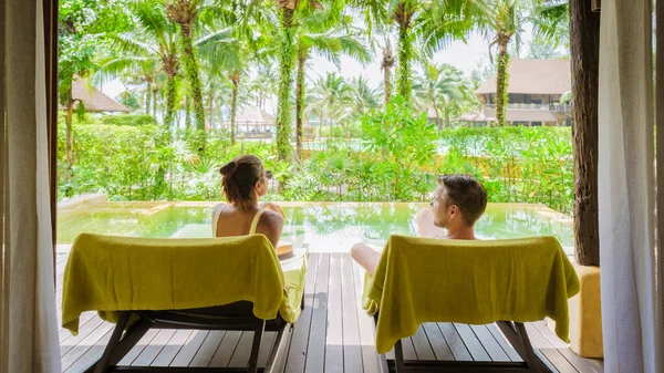 a couple of men and woman on a luxury vacation in Thailand at a 5 star resort relaxing in the swimming pool of a luxury villa in Thailand