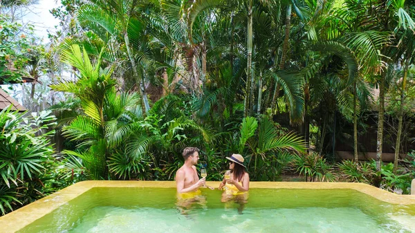 a couple of men and woman on a luxury vacation in Thailand at a 5 star resort relaxing in the swimming pool of a luxury villa in Thailand