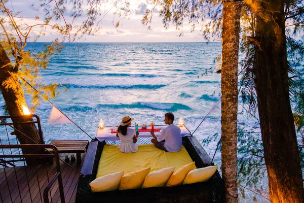 Romantic dinner on the beach in Koh Kood Thailand, a couple of men and woman having dinner on the beach high in the tree at a bird nest in Thailand during sunset in Ko Kut Trat during a luxury holiday