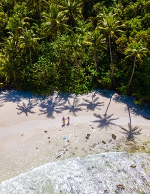 Ao Jark Körfezi ve Beach Koh Kood Adası Tayland Trat, palmiye ağaçları ve turkuaz renkli okyanuslu tropik plaj güneşli bir günde, Ko Kut Adası plajında yürüyen çift