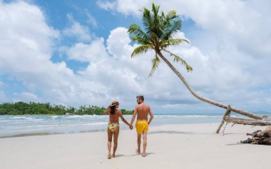 Gizli Kumsal Kood Adası Tayland Trat, güneşli bir günde, tropik bir plajda palmiye ağaçları ve turkuaz renkli bir okyanusta yürüyen birkaç erkek ve kadın.