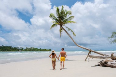 Gizli Kumsal Koh Kood Adası Tayland Trat, güneşli bir günde, tropik bir plajda palmiye ağaçları ve turkuaz renkli bir okyanusta yürüyen çeşitli erkek ve kadınlar.
