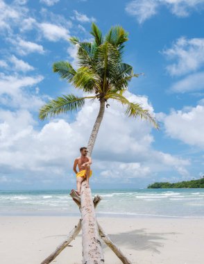 Tayland 'da tatil sırasında Koh Kood Tayland sahilinde asılı bir palmiye ağacında yüzen genç erkekler